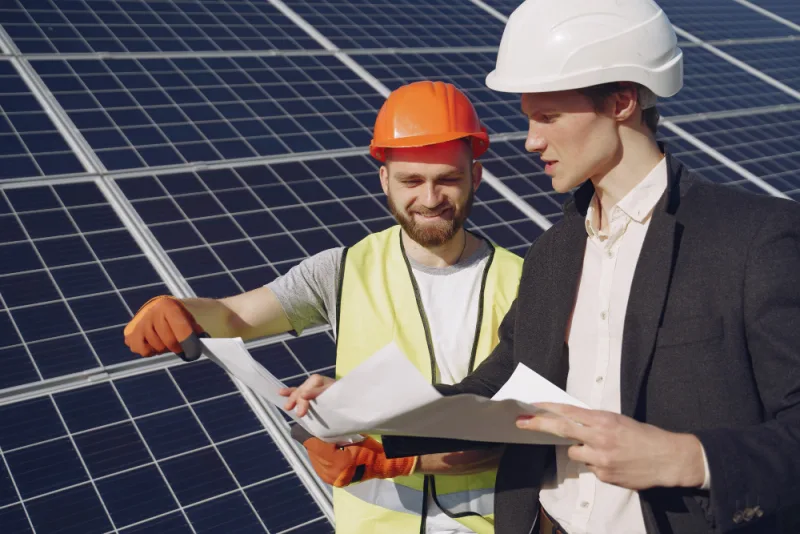 Two people reviewing documents in front of solar panels