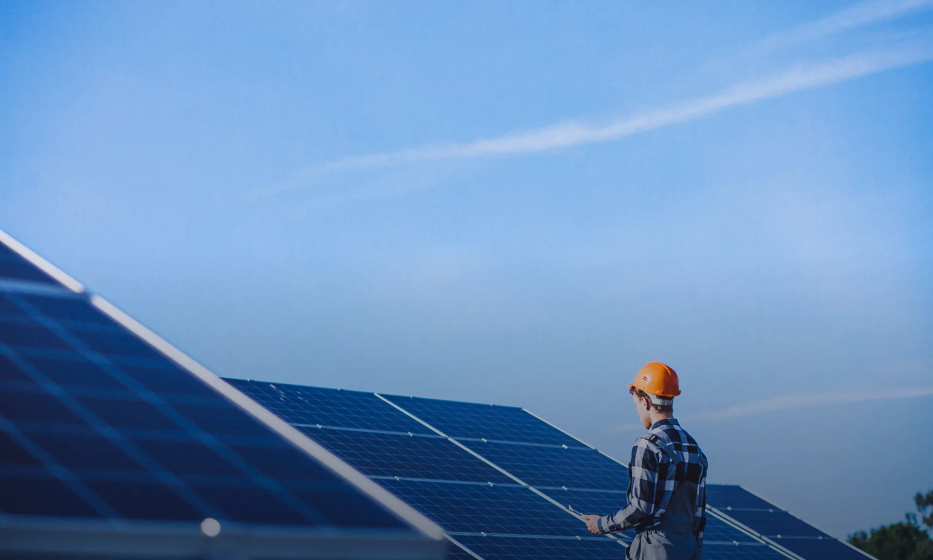 A technician inspecting alongside rows of solar panels